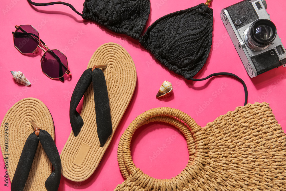 Flip flops with swimsuit, sunglasses and bag on pink background