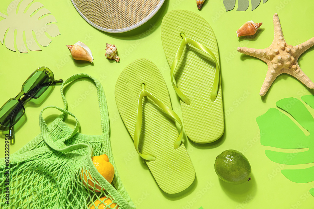 Flip flops with bag, sunglasses and tennis hat on green background