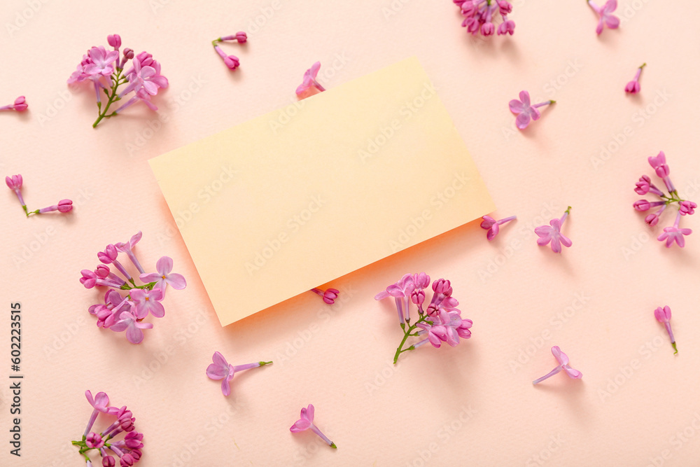 Blank card and beautiful lilac flowers on pale pink background