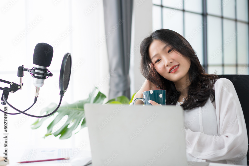 Asian woman working on laptop computer with headphones and microphone at home relaxing and chilling 