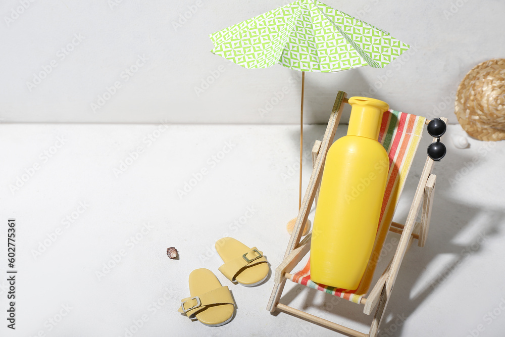 Creative composition with beach accessories and sunscreen on white table near wall