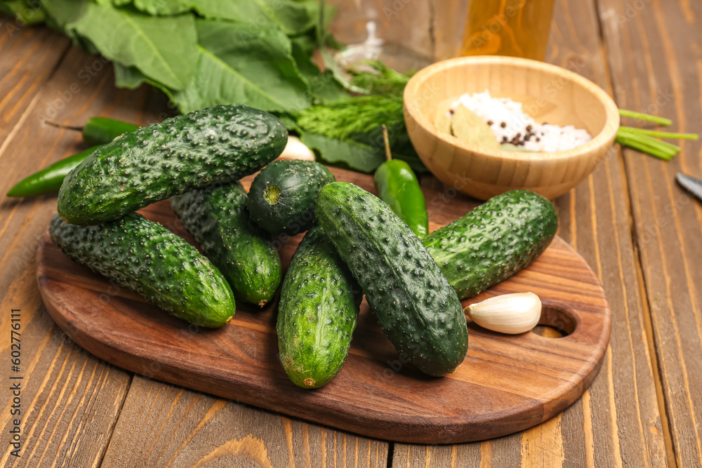 Board with fresh cucumbers for preservation on wooden background