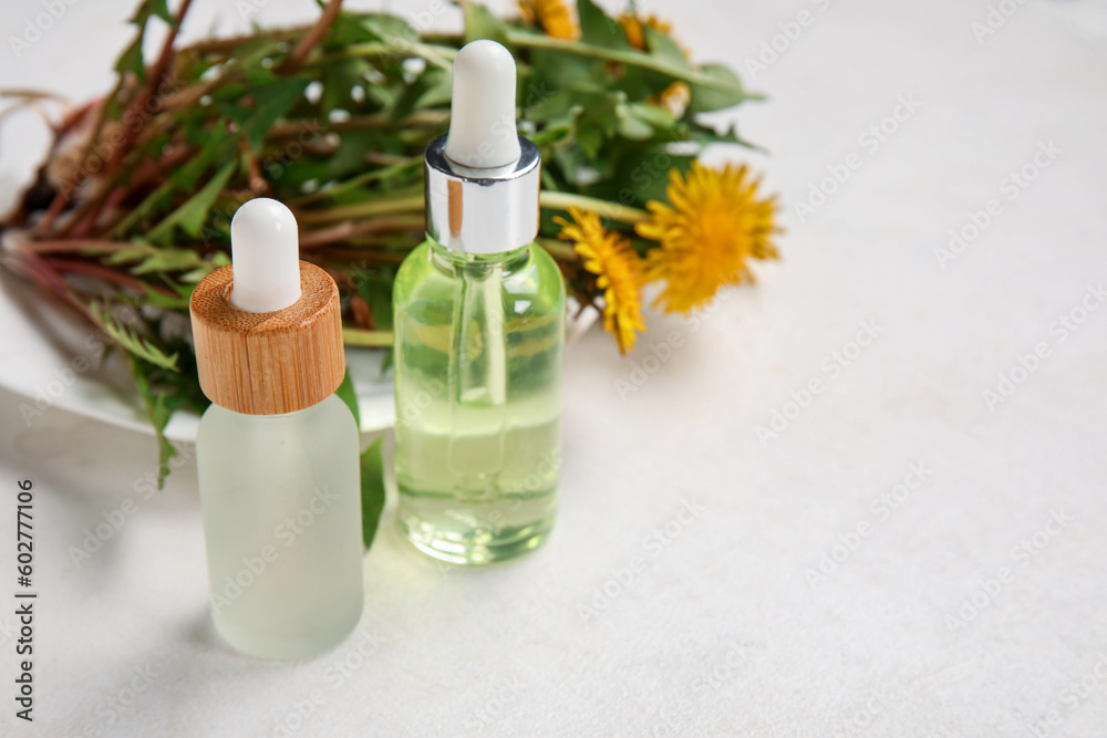 Bottles with cosmetic oil and plate of dandelion flowers on white background