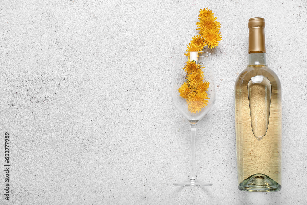 Bottle and glass of dandelion wine on white background