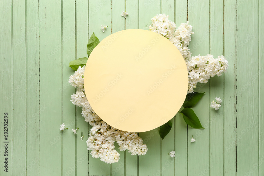 Blank card and frame made of lilac flowers on green wooden background