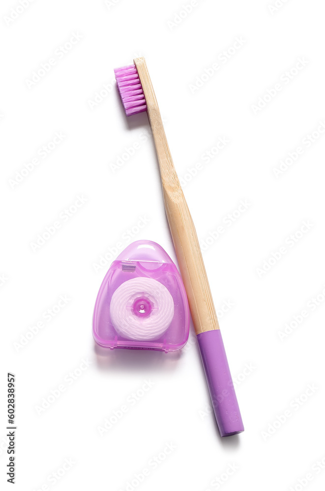 Dental floss and bamboo toothbrush isolated on white background