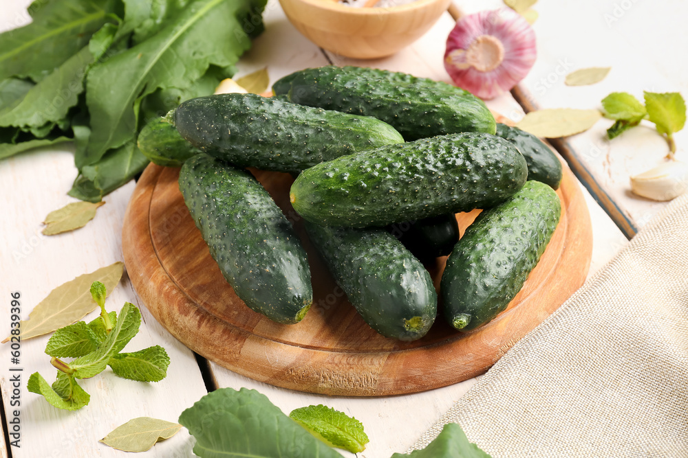 Board with fresh cucumbers for preservation on light wooden background