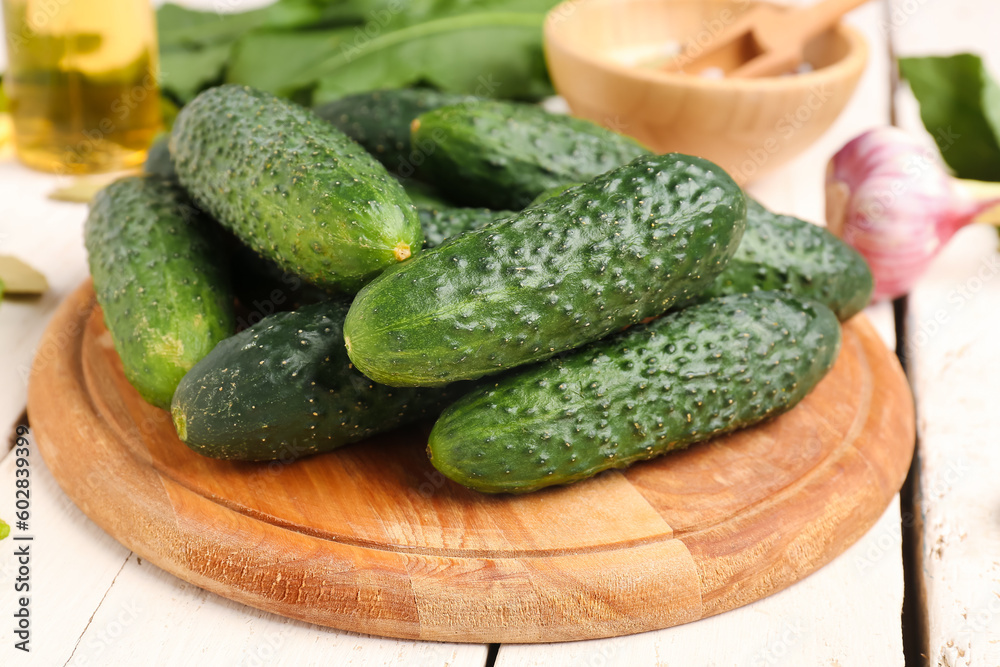 Wooden board with fresh cucumbers for preservation on table