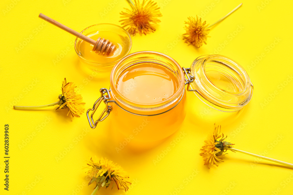 Jar and bowl with dandelion honey on yellow background