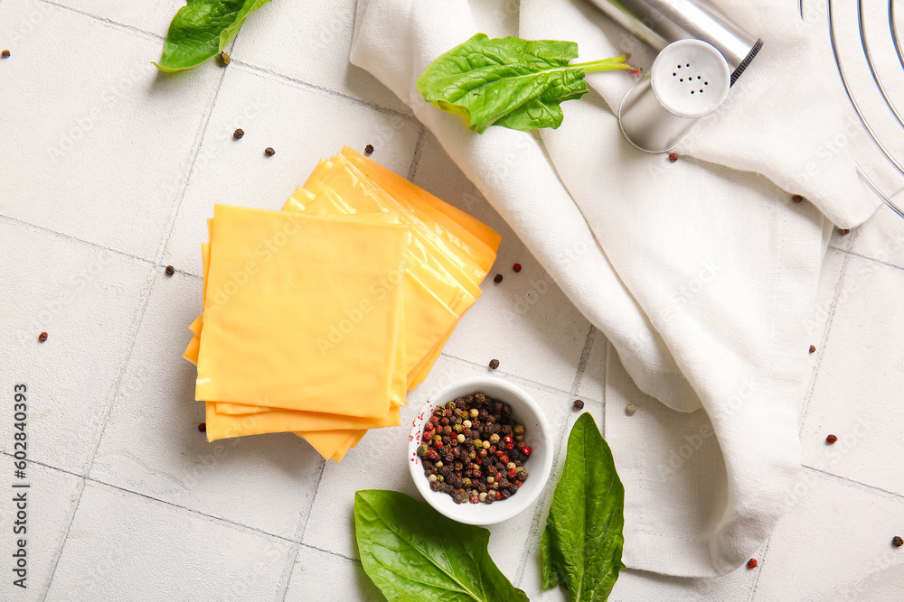 Slices of tasty processed cheese on white tile background