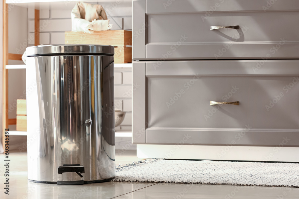 Metallic trash bin on floor in modern kitchen