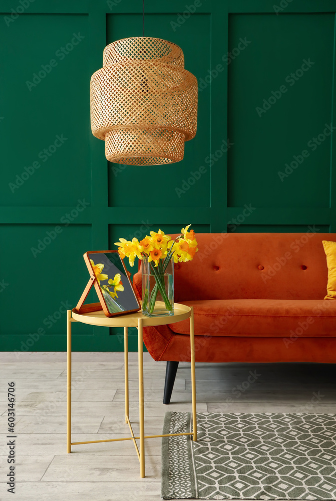 Vase with narcissus flowers and mirror on coffee table in living room