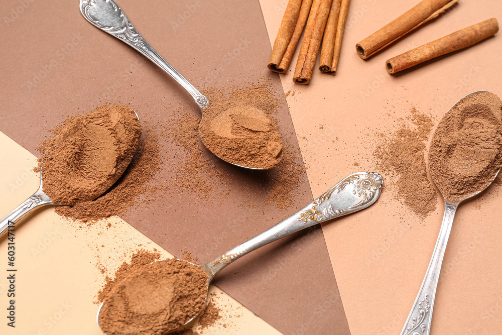 Composition with spoons of cinnamon powder and sticks on color background