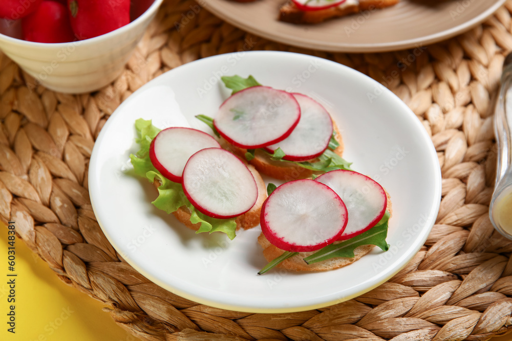 Plate with delicious radish bruschettas on wicker mat, closeup