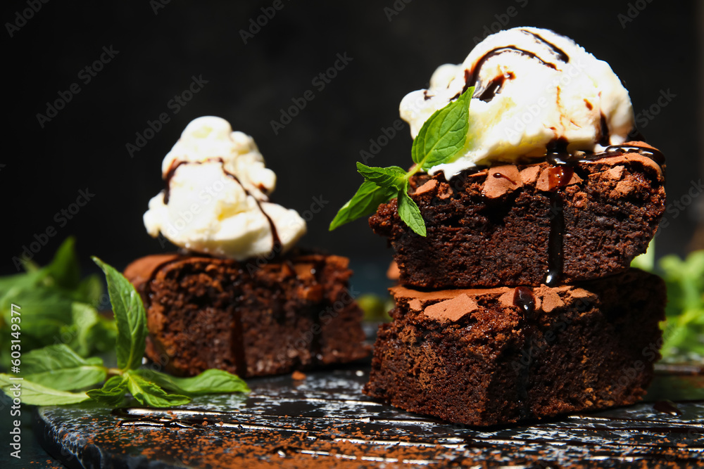 Board with pieces of tasty chocolate brownie and ice cream on dark background