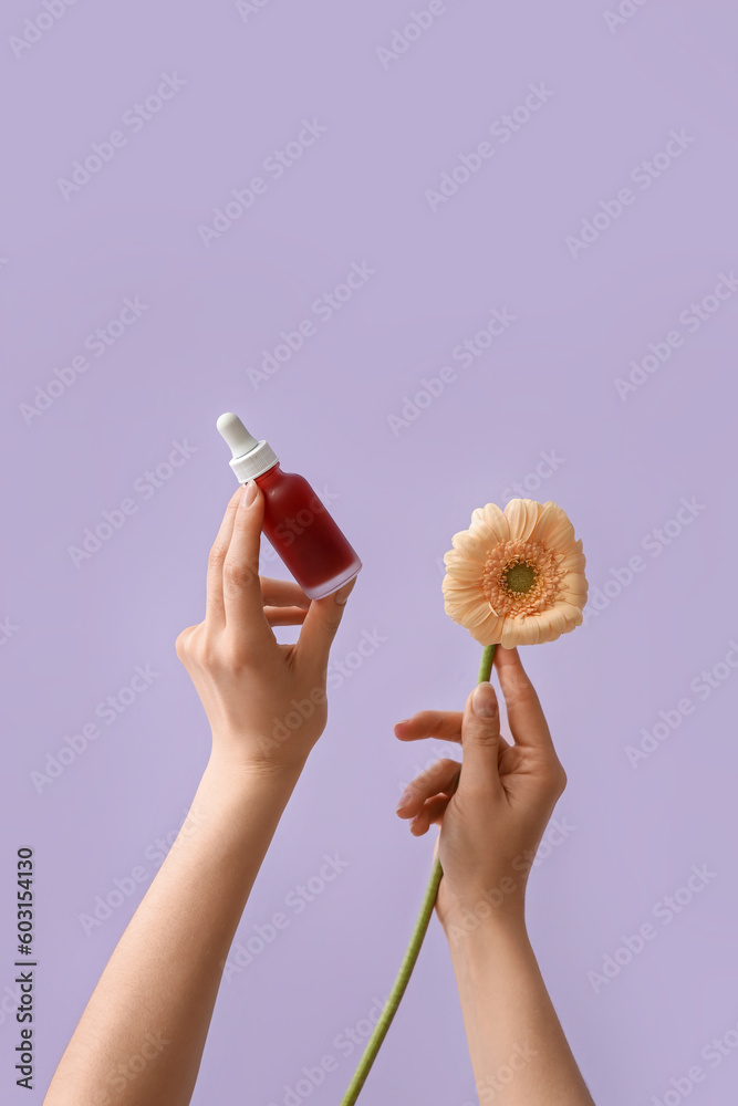 Hands holding bottle of cosmetic product and flower on lilac background