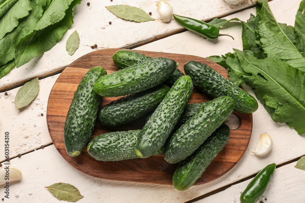 Board with fresh cucumbers for preservation on light wooden background