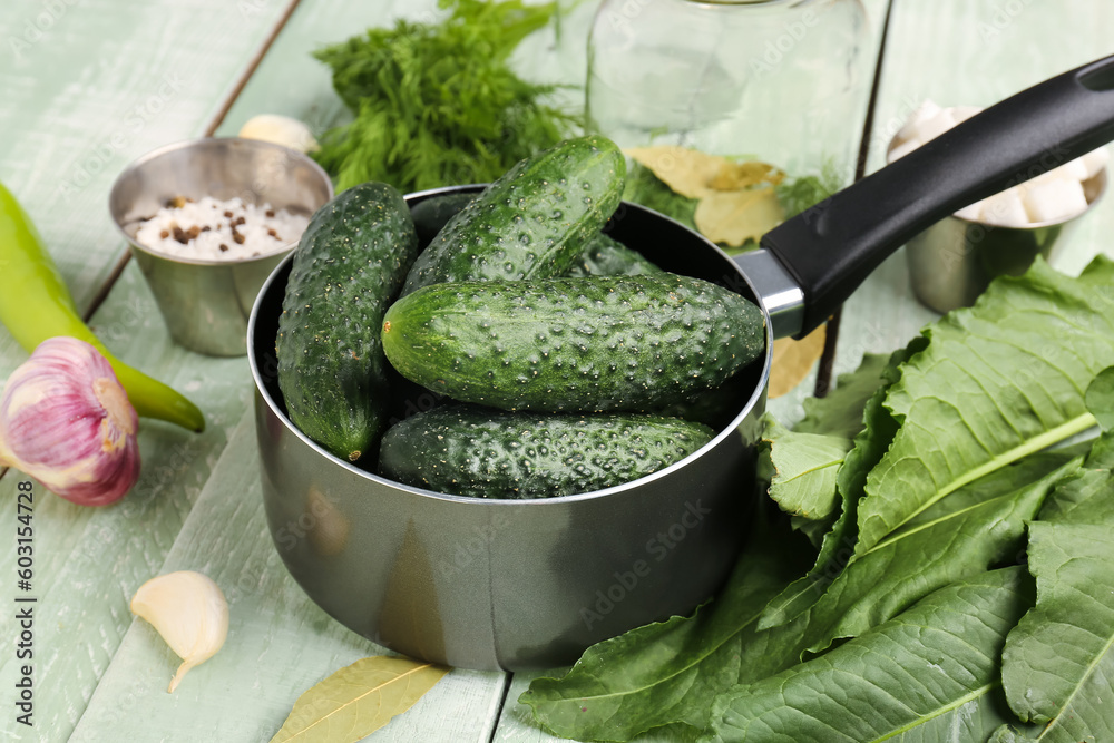 Saucepan with fresh cucumbers for preservation on light wooden background