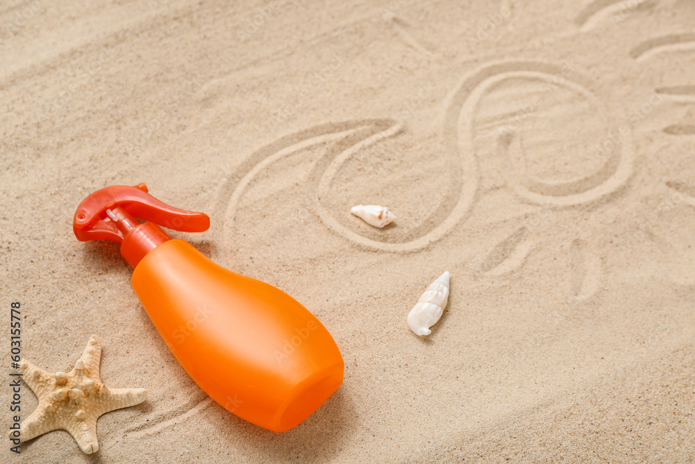 Creative composition with spray bottle of sunscreen cream with drawings on sand