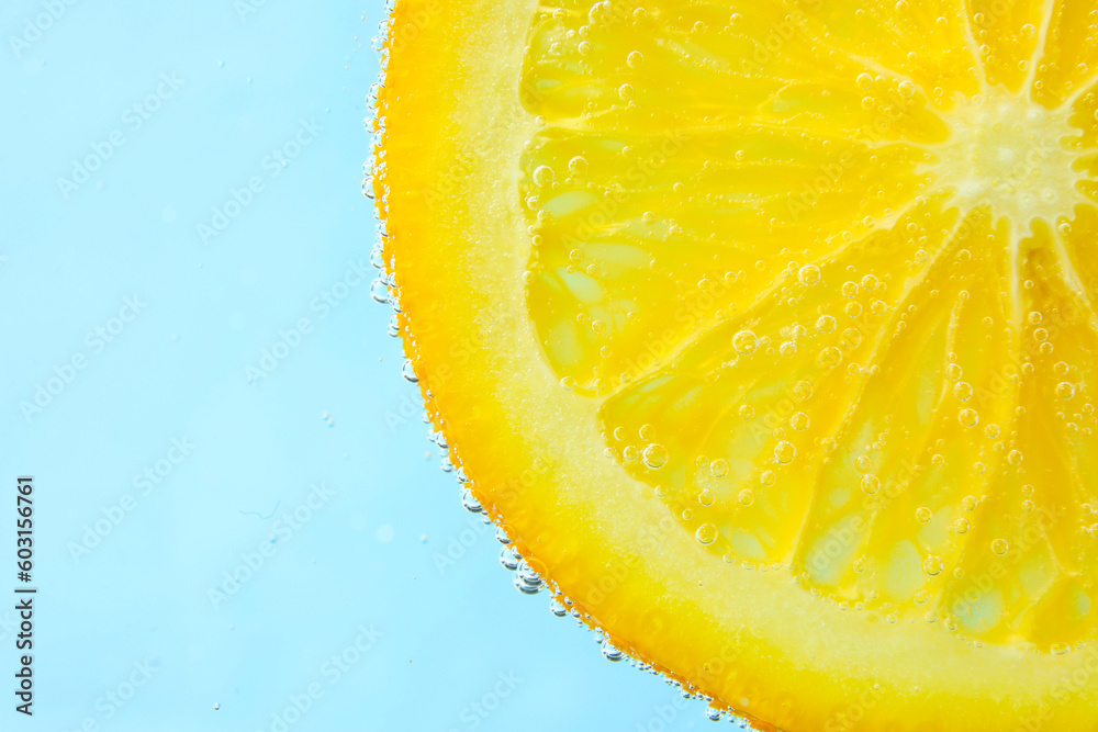 Orange slice in water with bubbles on blue background