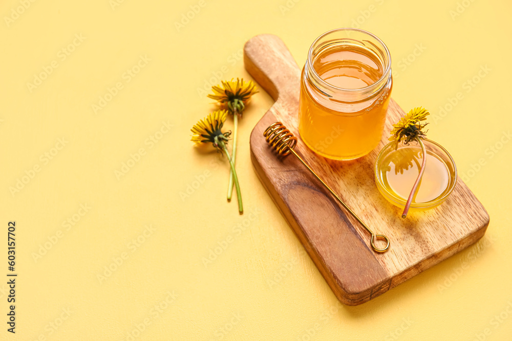 Board, jar and bowl with dandelion honey on yellow background