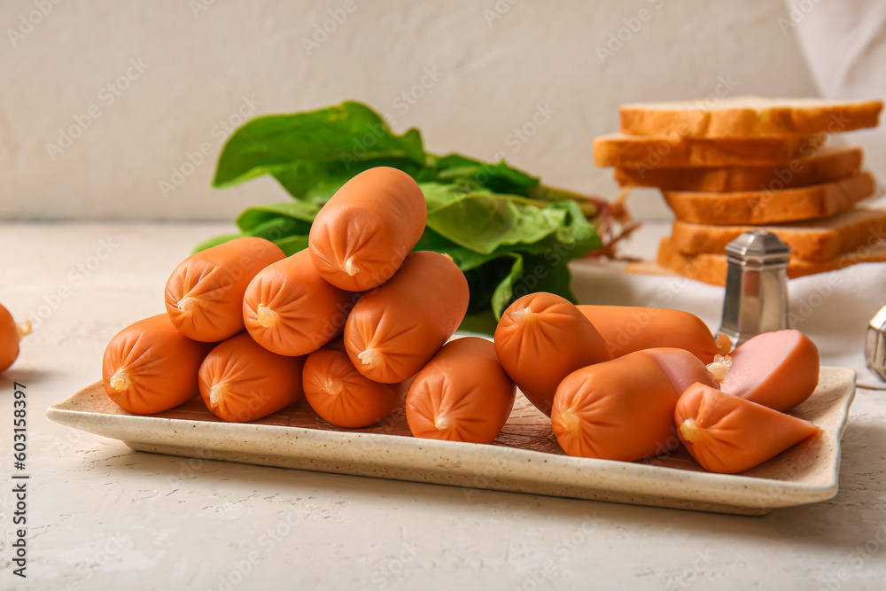 Plate of tasty boiled sausages and spinach on white background