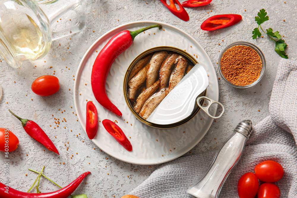 Plate of canned smoked sprats and chilli on grey background