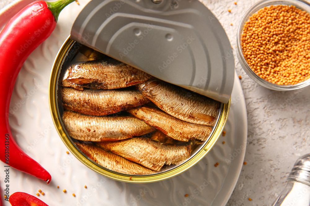 Plate of canned smoked sprats and chilli on grey background