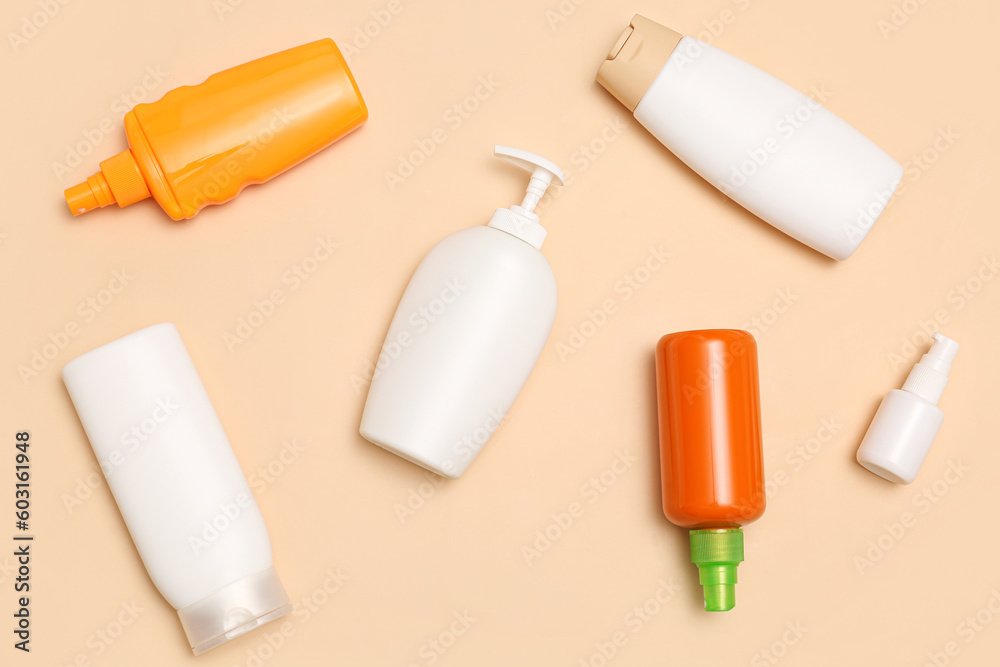 Different bottles of sunscreen cream on pale orange background