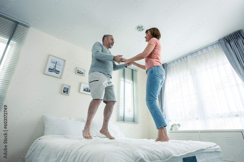 Caucasian senior couple dancing with music together in bedroom at home. 