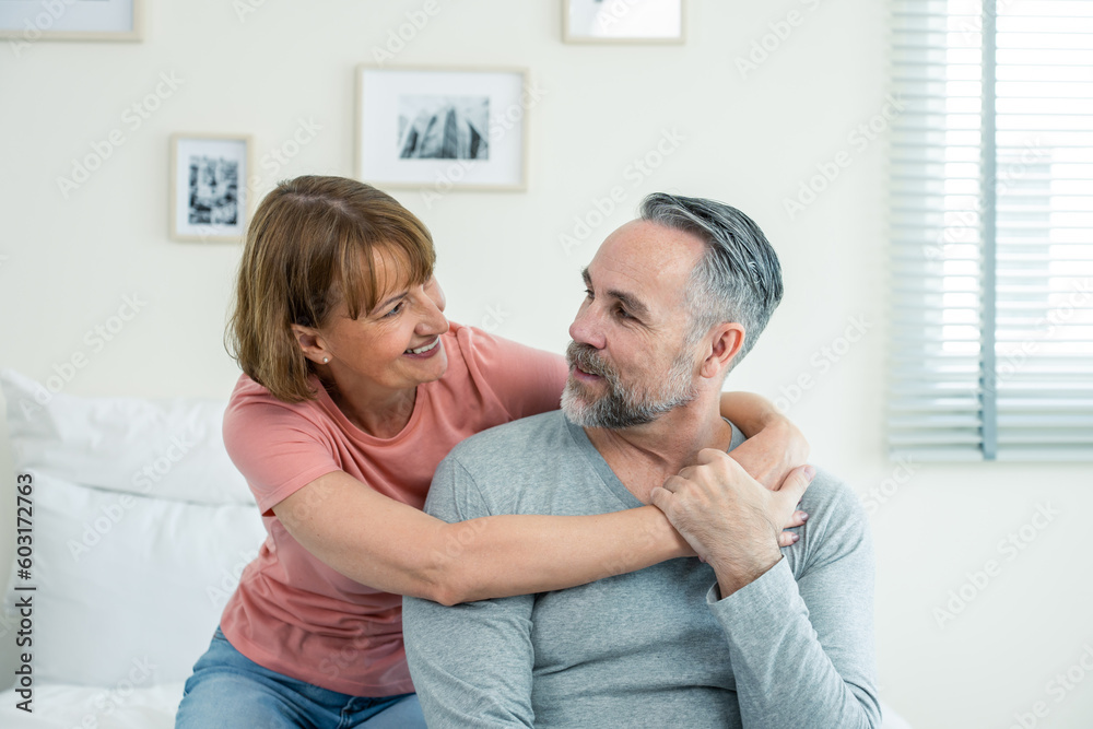 Caucasian senior older couple sitting on bed then look at each other.