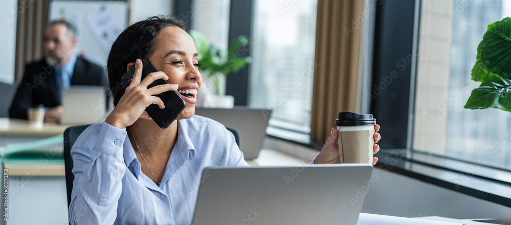 Latino happy businesswoman talking on smartphone and working in office. 