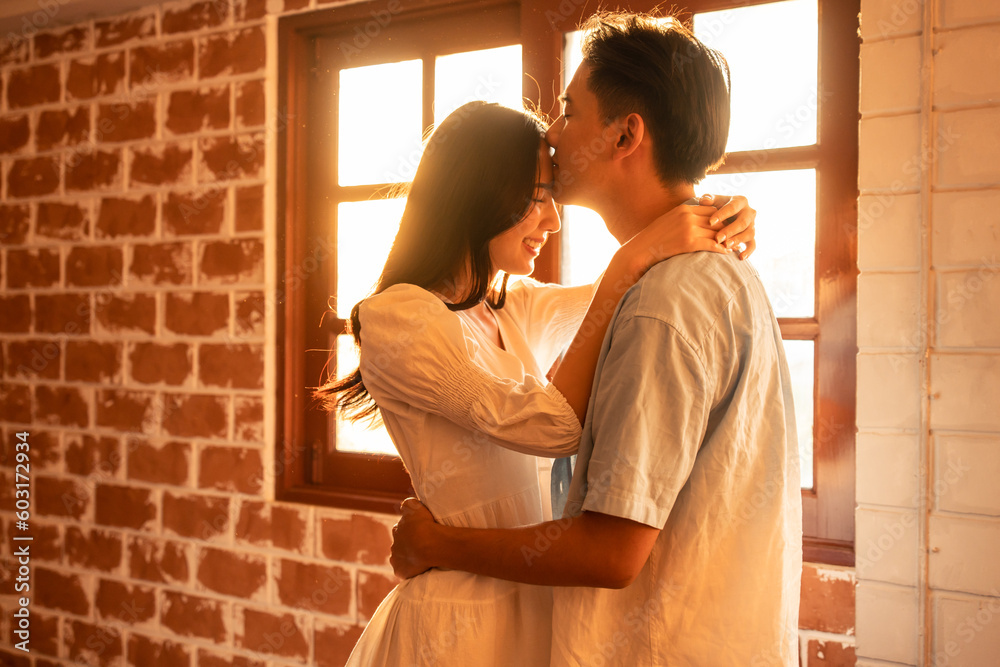 Asian young man and woman kissing each other in living room at home.