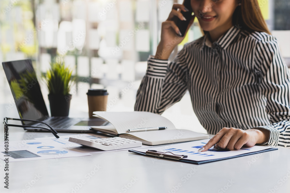 Businesswoman doing accounting work in the office analyzing charts in financial reports with a calcu