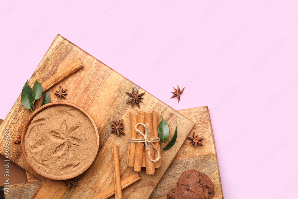 Wooden boards with bowl of cinnamon powder, sticks, anise stars and cookies on color background