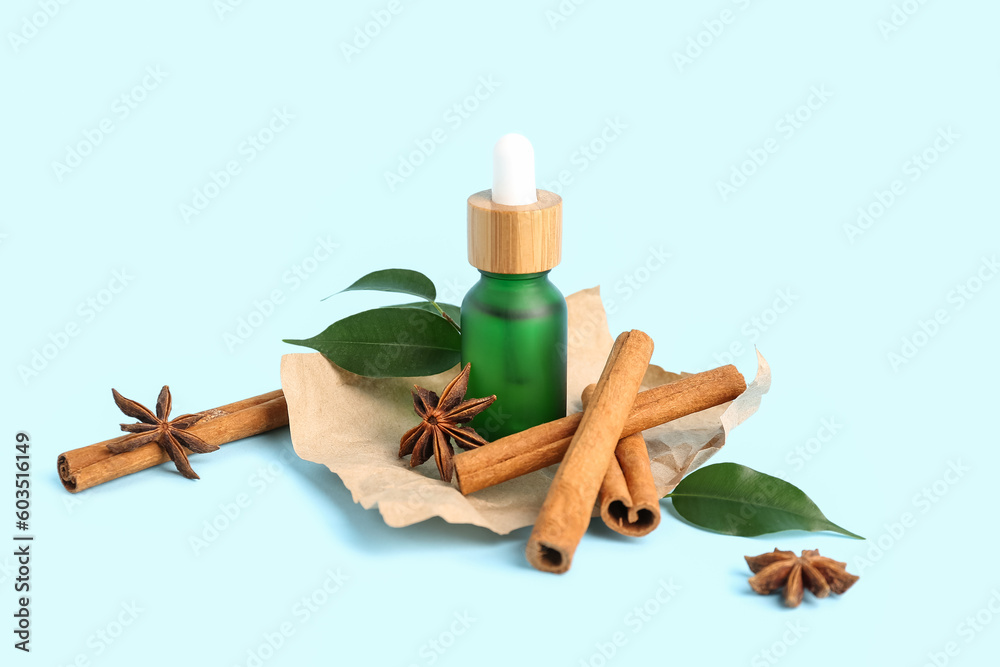 Bottle of essential oil, cinnamon sticks, anise stars and plant leaves on color background