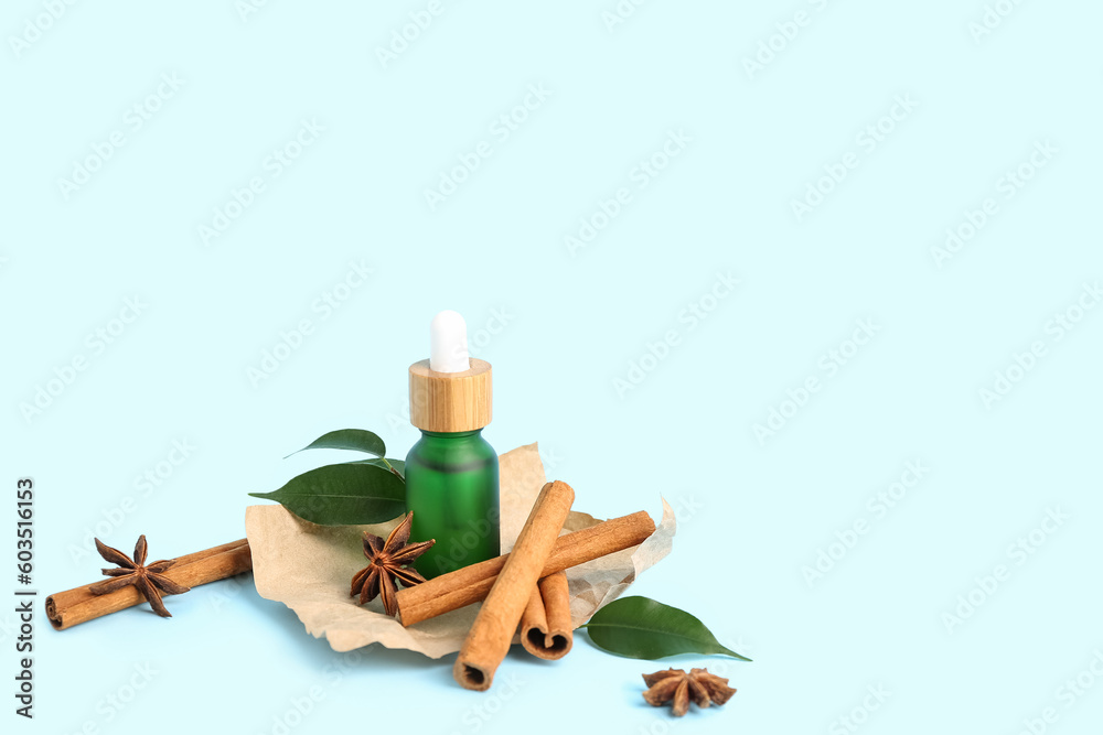 Bottle of essential oil, cinnamon sticks, anise stars and plant leaves on color background