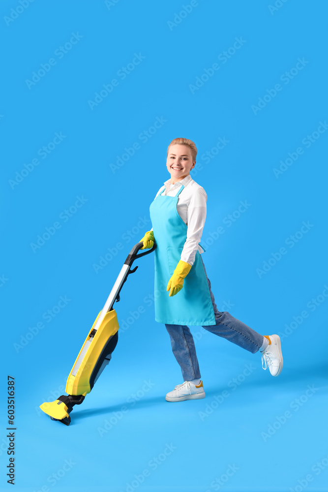 Young woman with vacuum cleaner on blue background