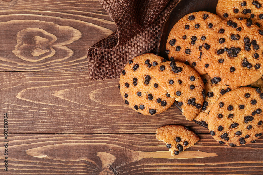 Plate of tasty cookies with chocolate chips on wooden background, closeup