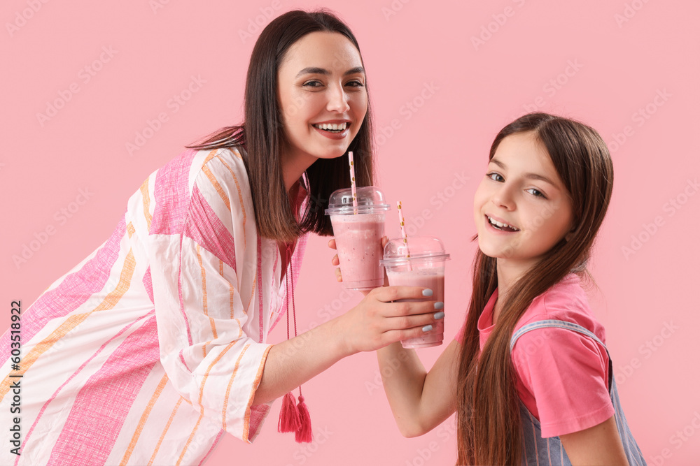 Little girl with her mother drinking smoothie on pink background