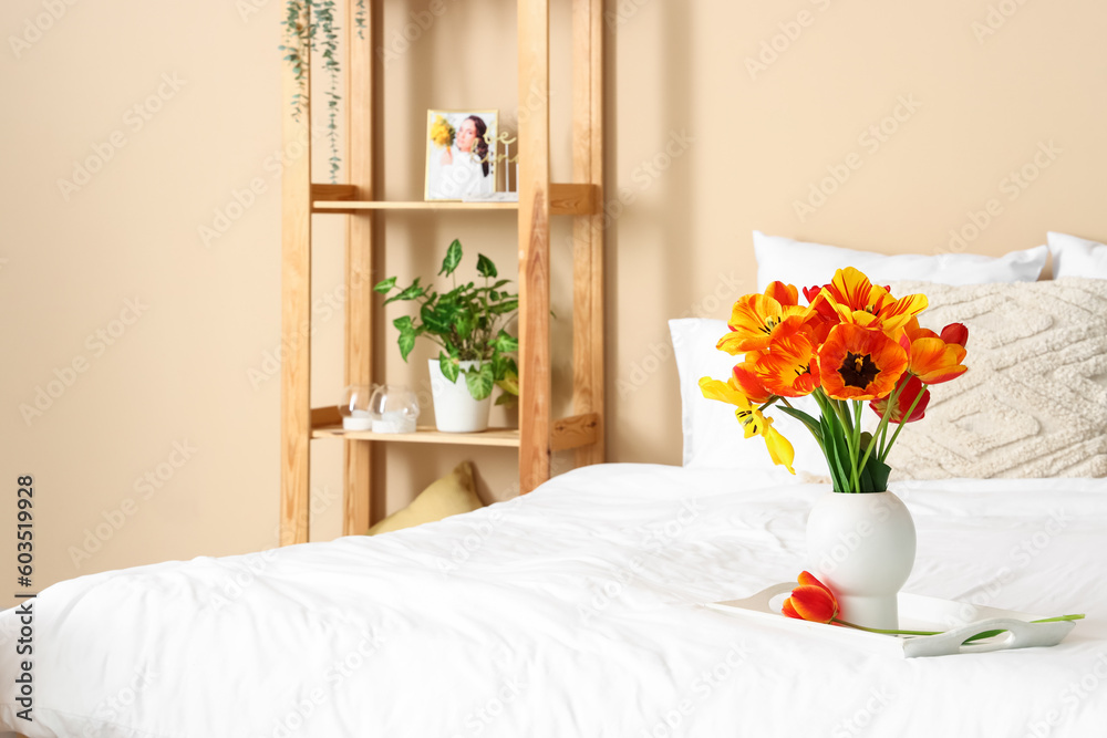 Vase with beautiful tulip flowers on bed, closeup