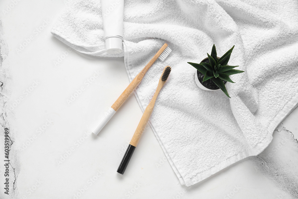 Bamboo toothbrushes with towel on white marble background