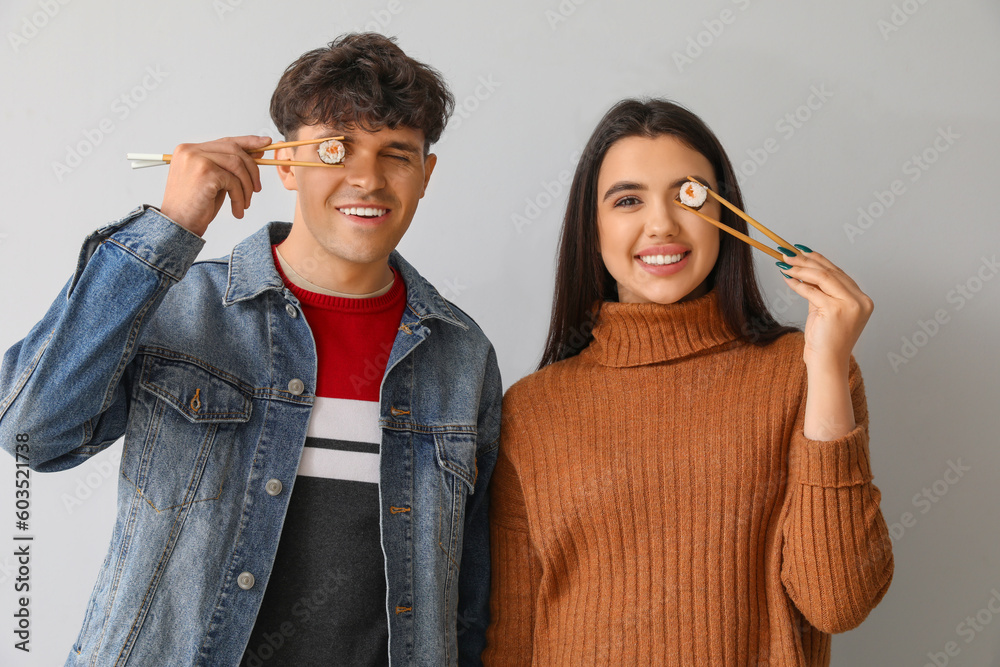 Young couple with sushi on light background