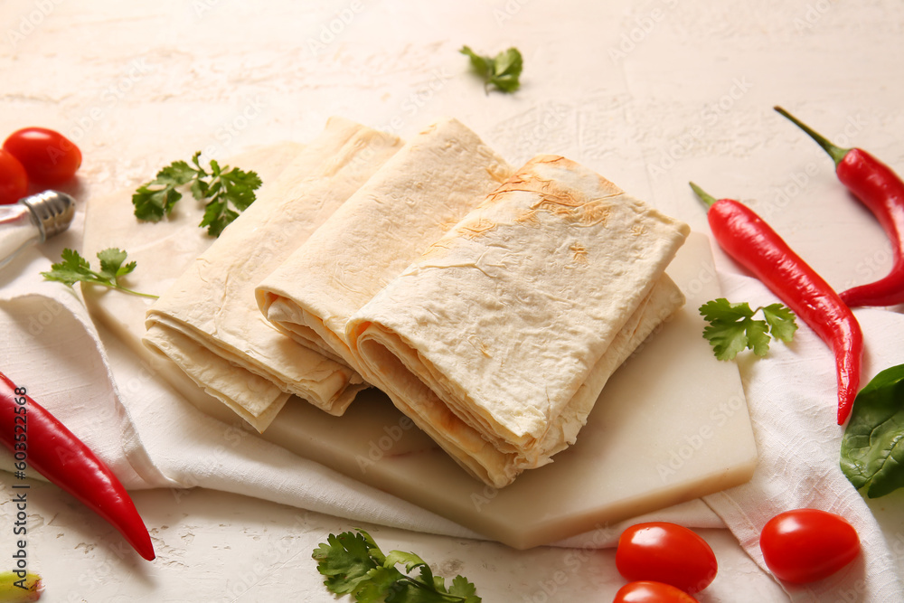 Board with fresh lavash on light background