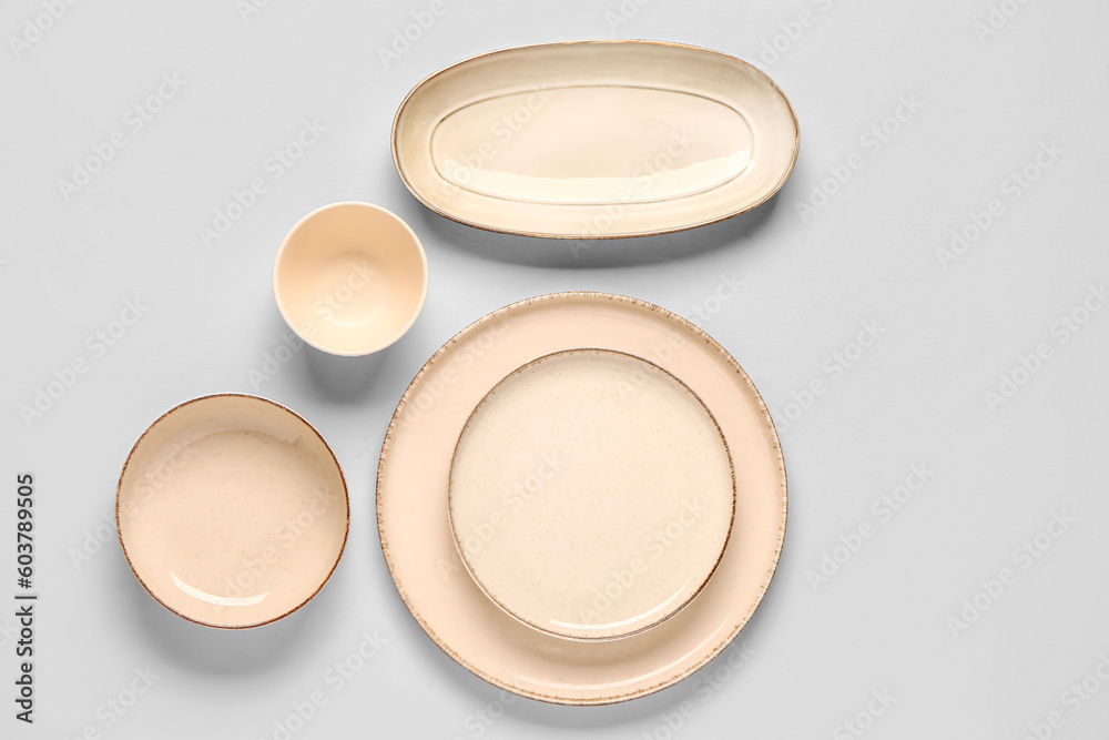 Composition with clean plates and bowl on grey background