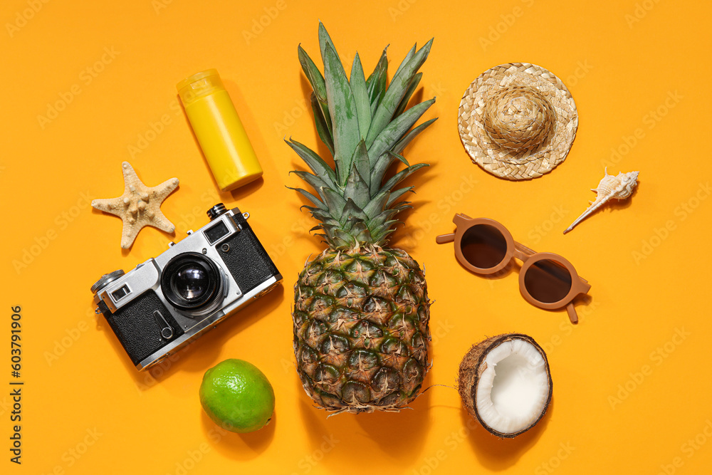 Photo camera with starfish, sunscreen cream, hat, fruits and sunglasses on orange background