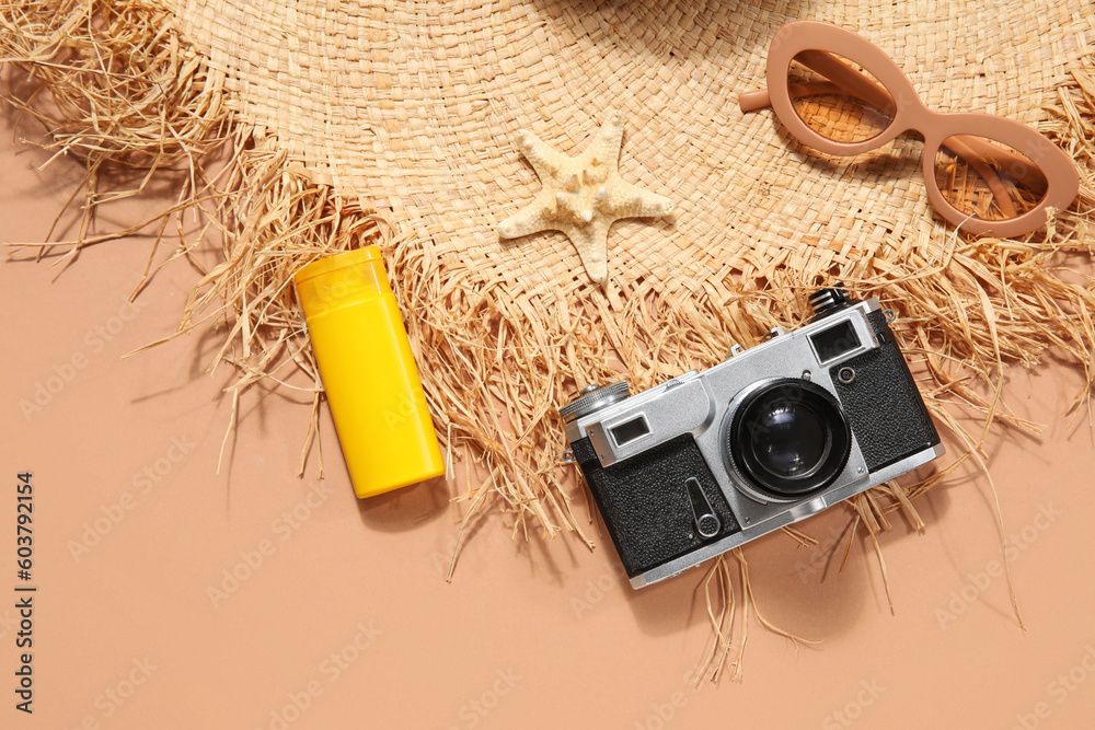 Summer hat with sunscreen cream, photo camera, starfish and sunglasses on beige background