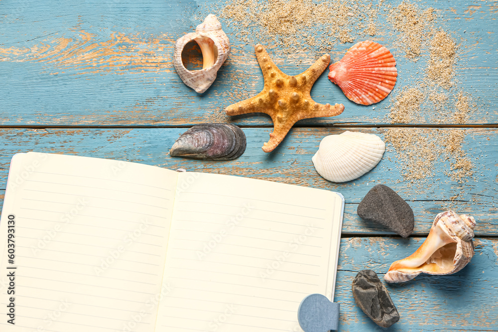 Blank notebook with seashells and starfish on blue wooden background