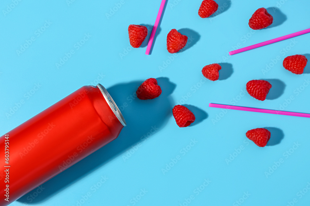 Composition with can of fresh soda and raspberry on blue background