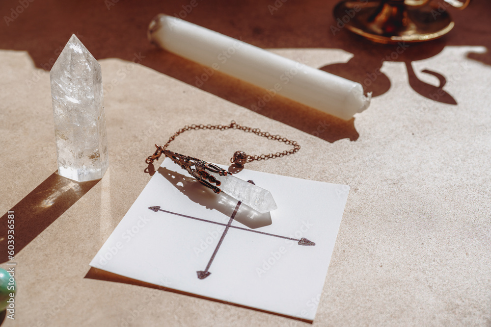 Gemstones for esoteric spiritual practice. Rock crystal pendulum on the table. Divination with a pen